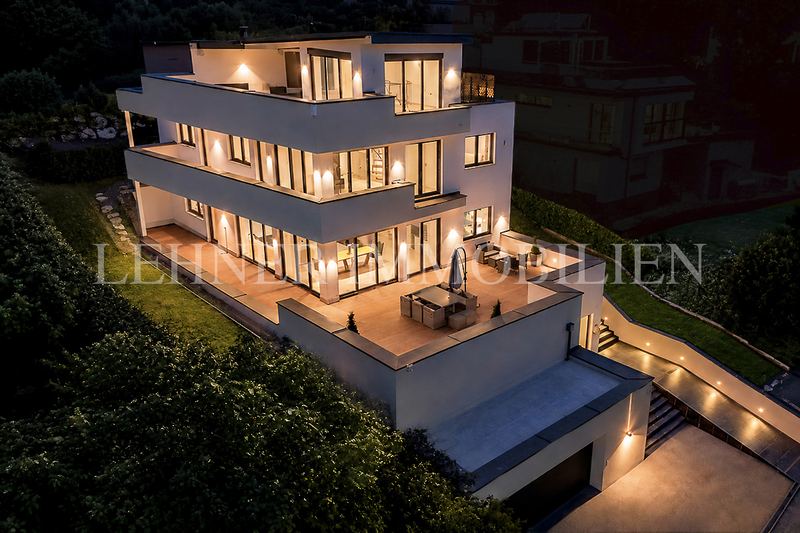 Abendliche Ansicht einer weißen Terrassenvilla mit beleuchteten Fenstern