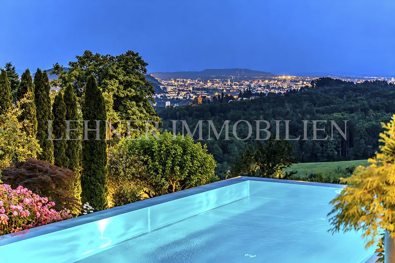 Infinity-Pool in der Dämmerung, im Hintergrund die beleuchtete Stadt Graz