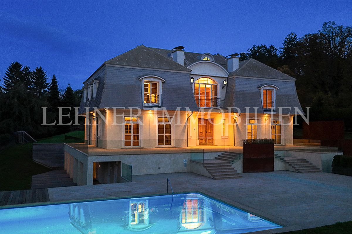 Beleuchtete Villa in der Dämmerung, davor ein erleuchteter Pool