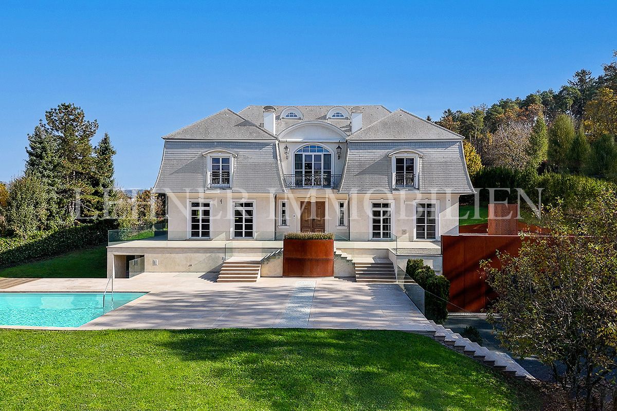 Villa mit hellem Mansarddach, Terrasse und Pool im Vordergrund
